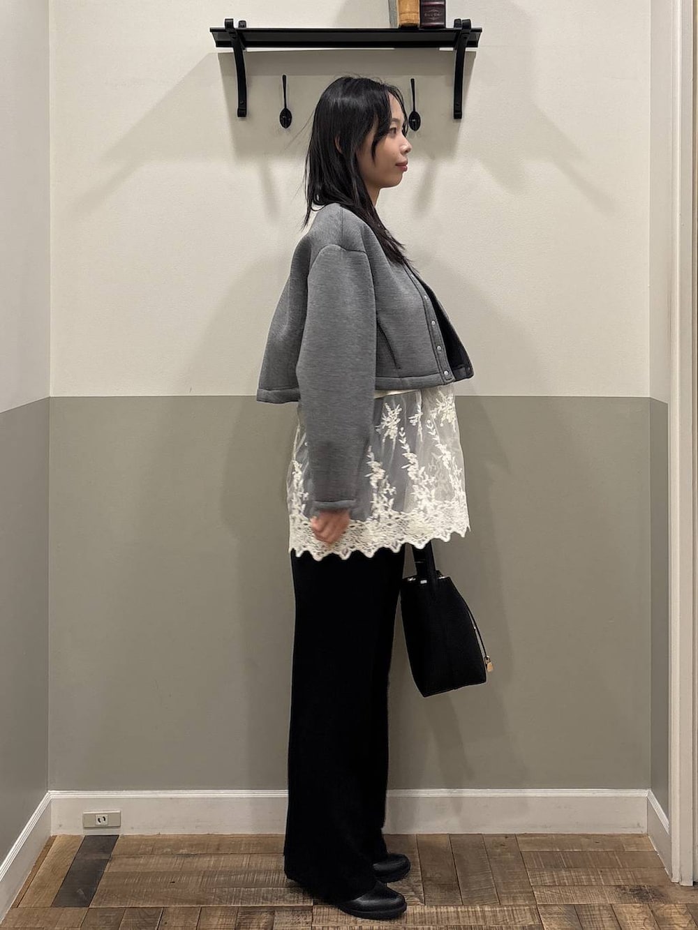 ホワイト系のチュニック、ブラック系のスーツセット、グレー系のノーカラージャケットを着用したレディースの春コーディネートの2枚目の写真