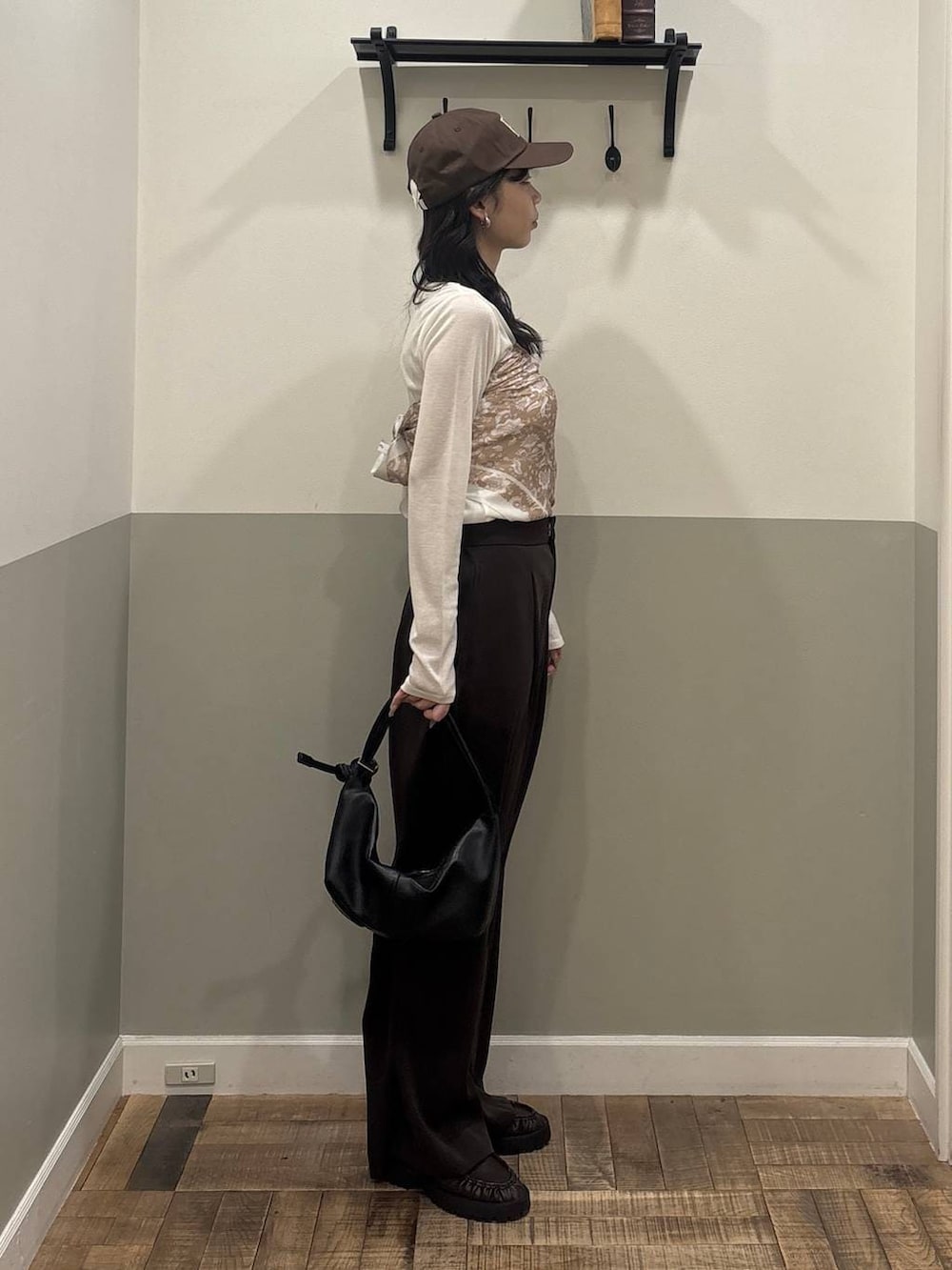 ブラウン系のスラックス、ブラック系のショルダーバッグ、ブラウン系のローファーを着用したレディースの冬コーディネートの2枚目の写真