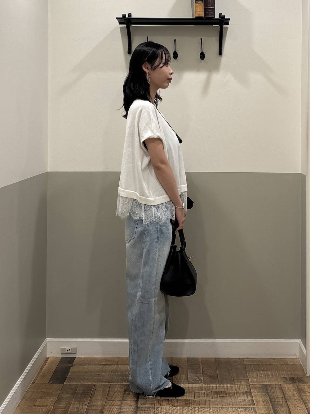ブルー系のデニムパンツ、ブラック系のショルダーバッグ、ホワイト系のニット/セーターを着用したレディースの夏コーディネートの2枚目の写真