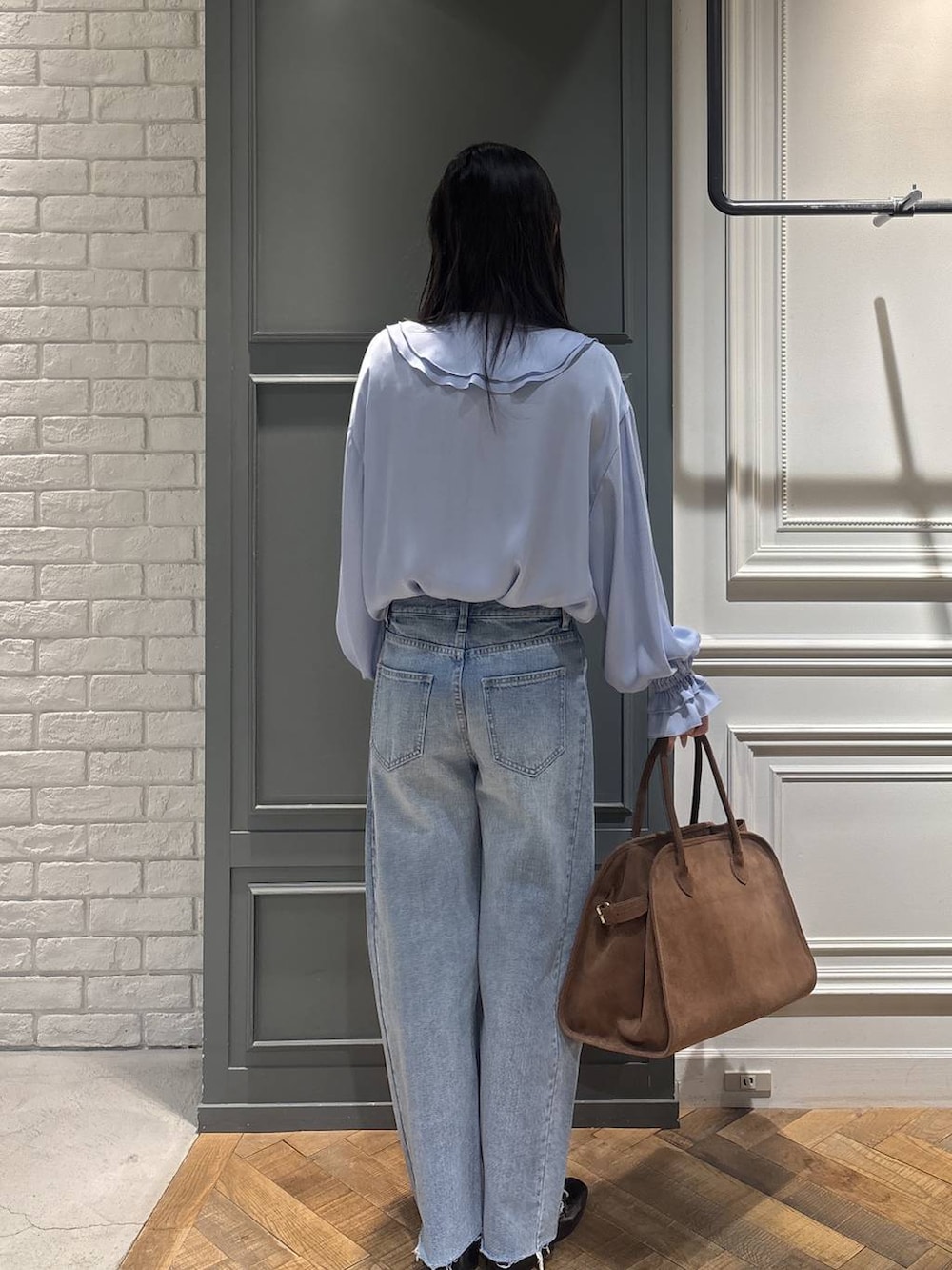 ブラウン系のショルダーバッグ、ブルー系のデニムパンツ、ブラック系のローファーを着用したレディースの冬コーディネートの2枚目の写真