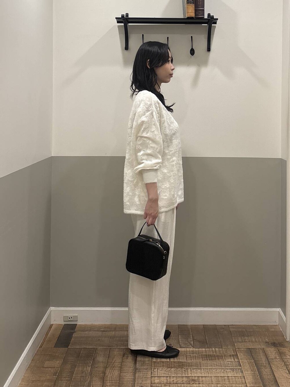 ホワイト系のニット/セーター、ブラック系のショルダーバッグ、ホワイト系のTシャツ/カットソーを着用したレディースの冬コーディネートの2枚目の写真