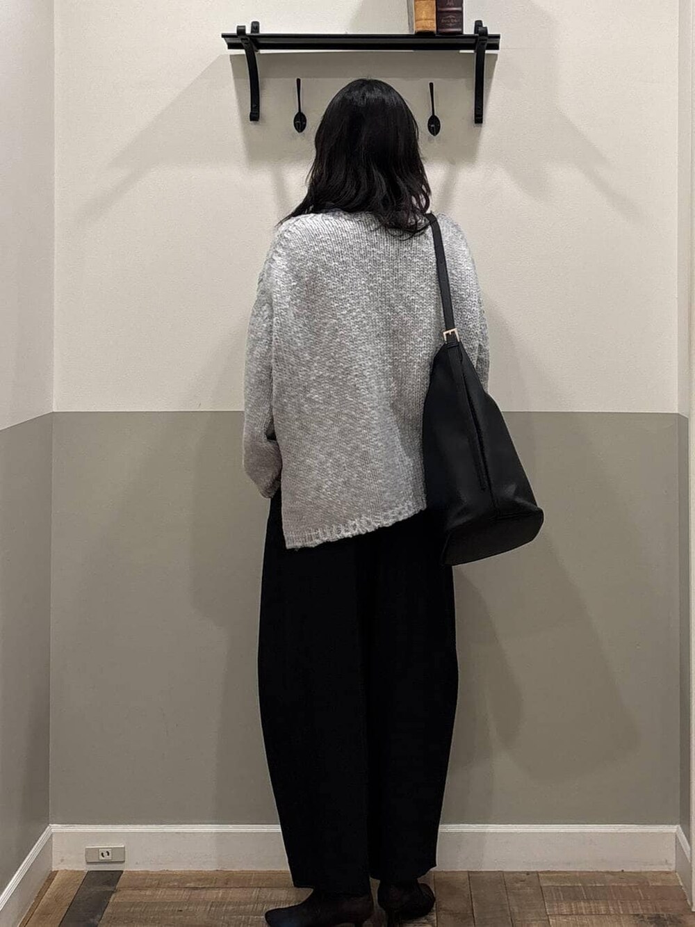 ブラック系のスラックス、グレー系のニット/セーター、ブラック系のトートバッグを着用したレディースの冬コーディネートの3枚目の写真