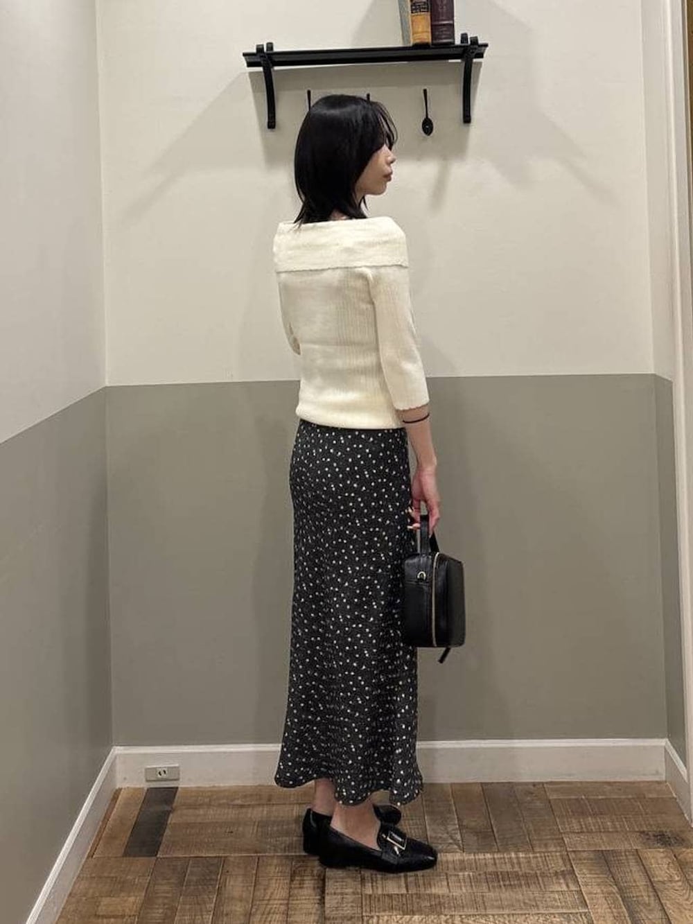 ブラック系のローファー、ホワイト系のニット/セーター、ブラック系のワンピースを着用したレディースの春コーディネートの2枚目の写真
