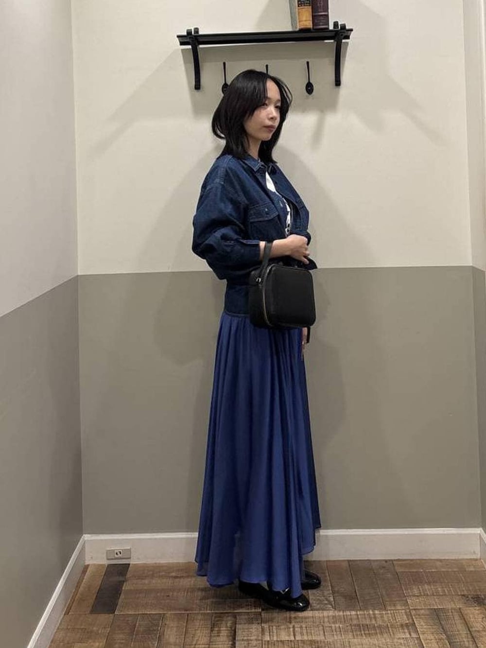 ブルー系のスカート、ブラック系のローファー、ブラック系のショルダーバッグを着用したレディースの春コーディネートの2枚目の写真