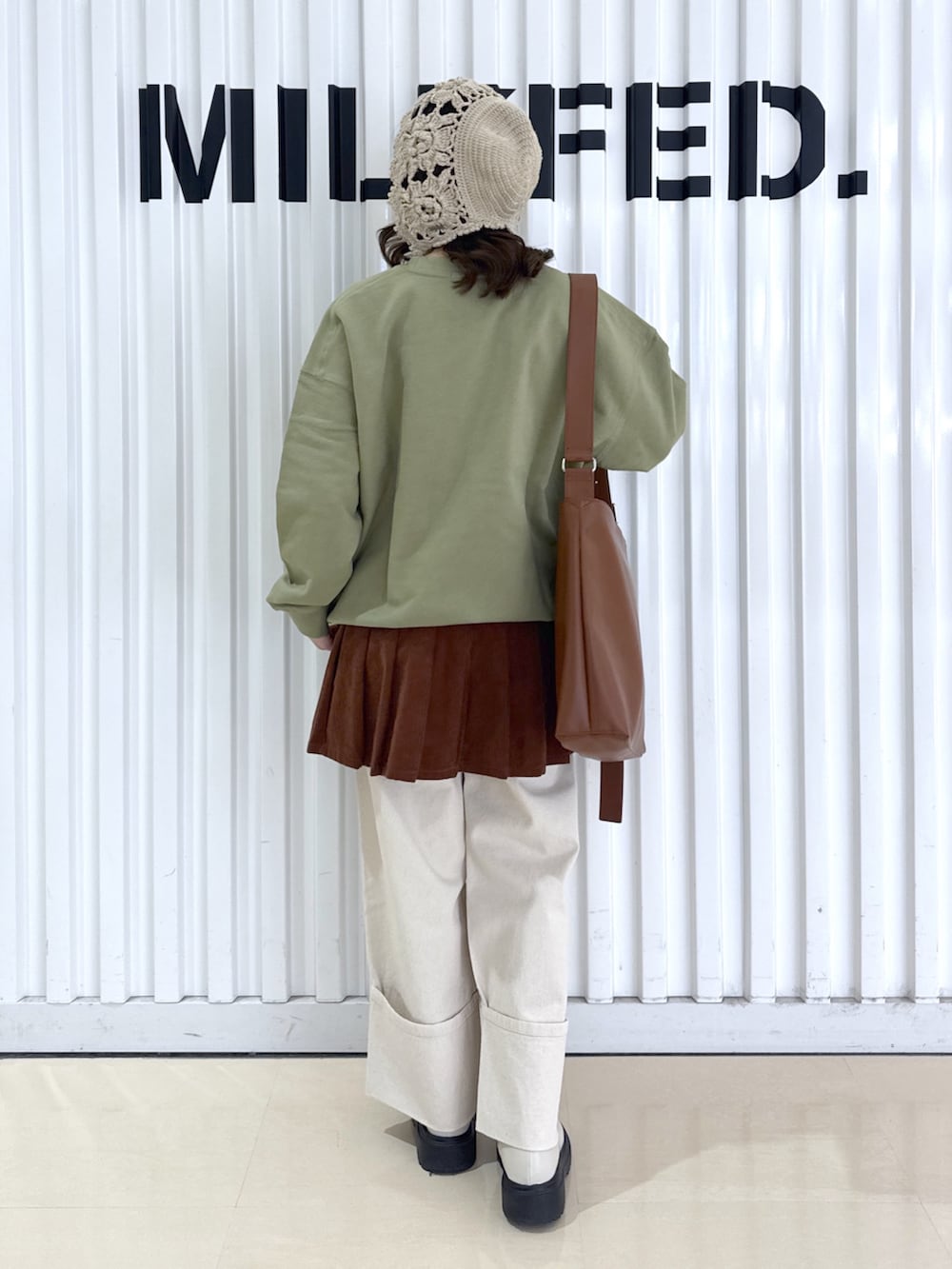 ホワイト系のデニムパンツ、グリーン系のスウェット、ブラウン系のショルダーバッグを着用したレディースの冬コーディネートの2枚目の写真