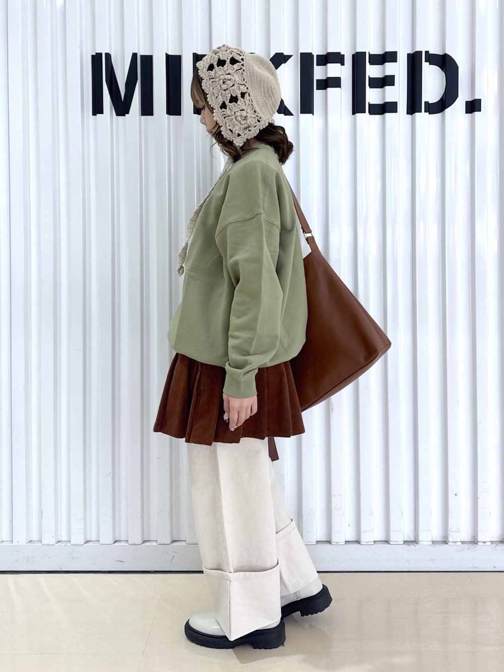 ホワイト系のデニムパンツ、グリーン系のスウェット、ブラウン系のショルダーバッグを着用したレディースの冬コーディネートの4枚目の写真