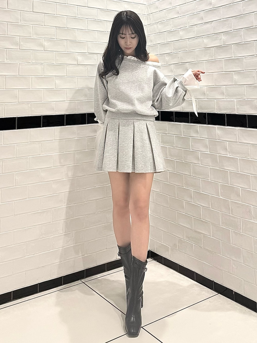 グレー系のTシャツ/カットソー、グレー系のスカート、ブラック系のブーツを着用したレディースの春コーディネートの4枚目の写真