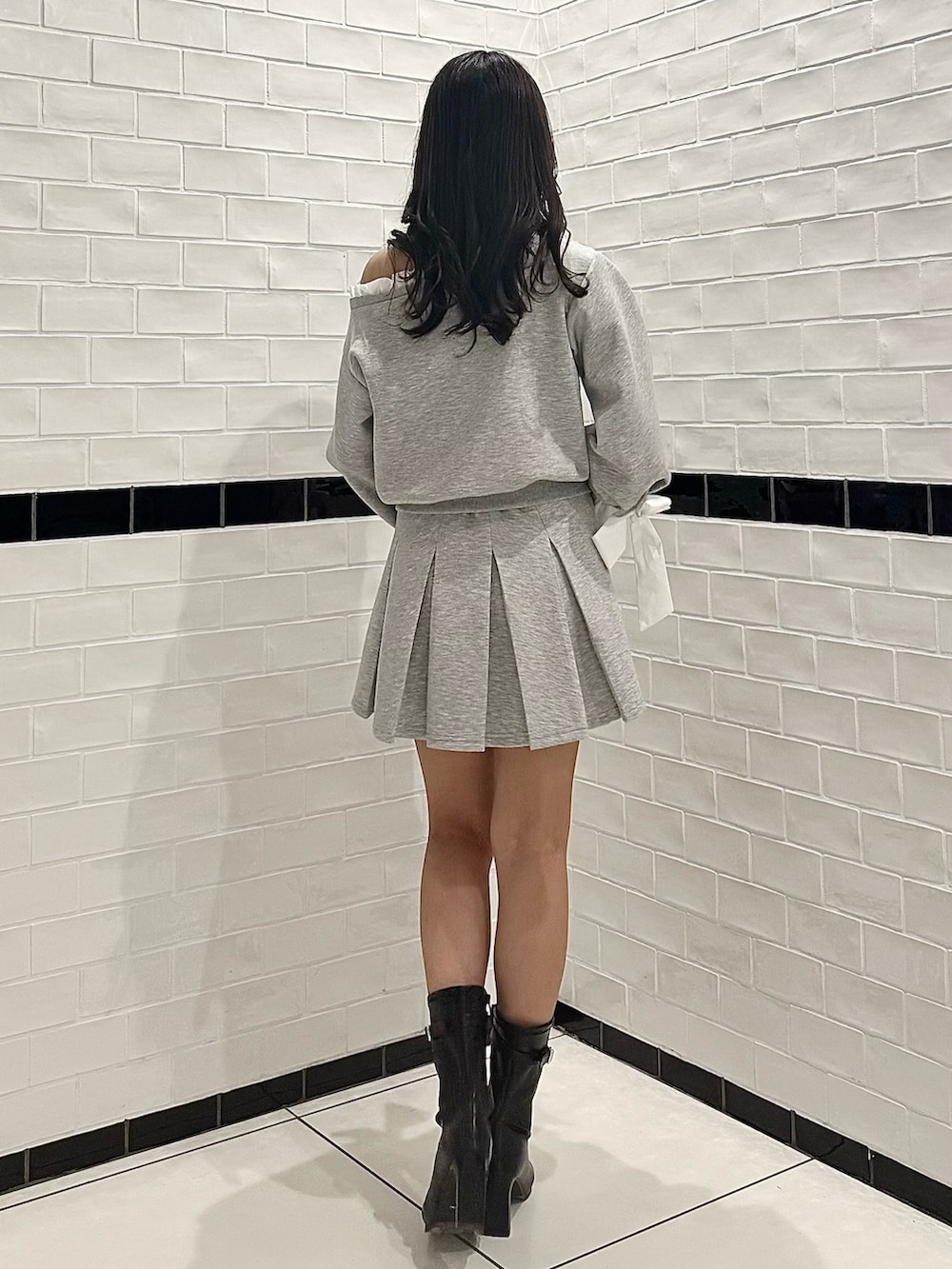グレー系のTシャツ/カットソー、グレー系のスカート、ブラック系のブーツを着用したレディースの春コーディネートの6枚目の写真