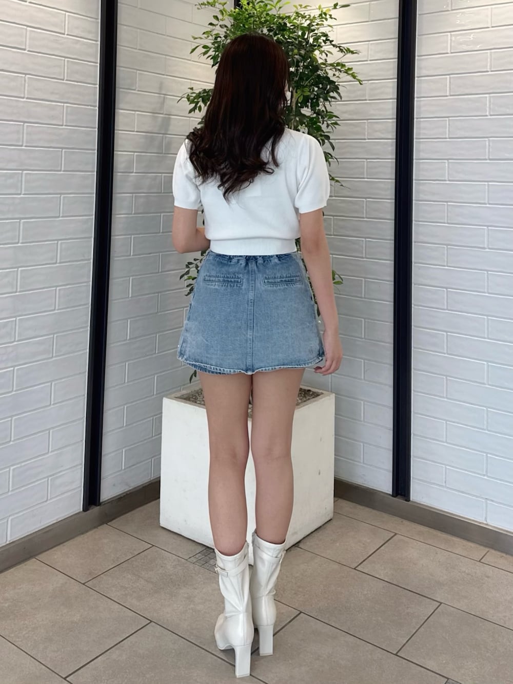 ホワイト系のニット/セーター、ブルー系のデニムパンツ、ホワイト系のブーツを着用したレディースの春コーディネートの5枚目の写真