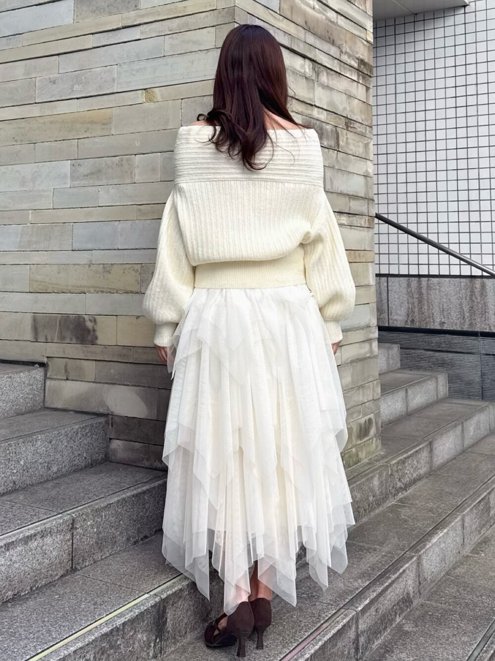 ブラウン系のパンプス、ホワイト系のニット/セーター、ホワイト系のスカートを着用したレディースの冬コーディネートの4枚目の写真