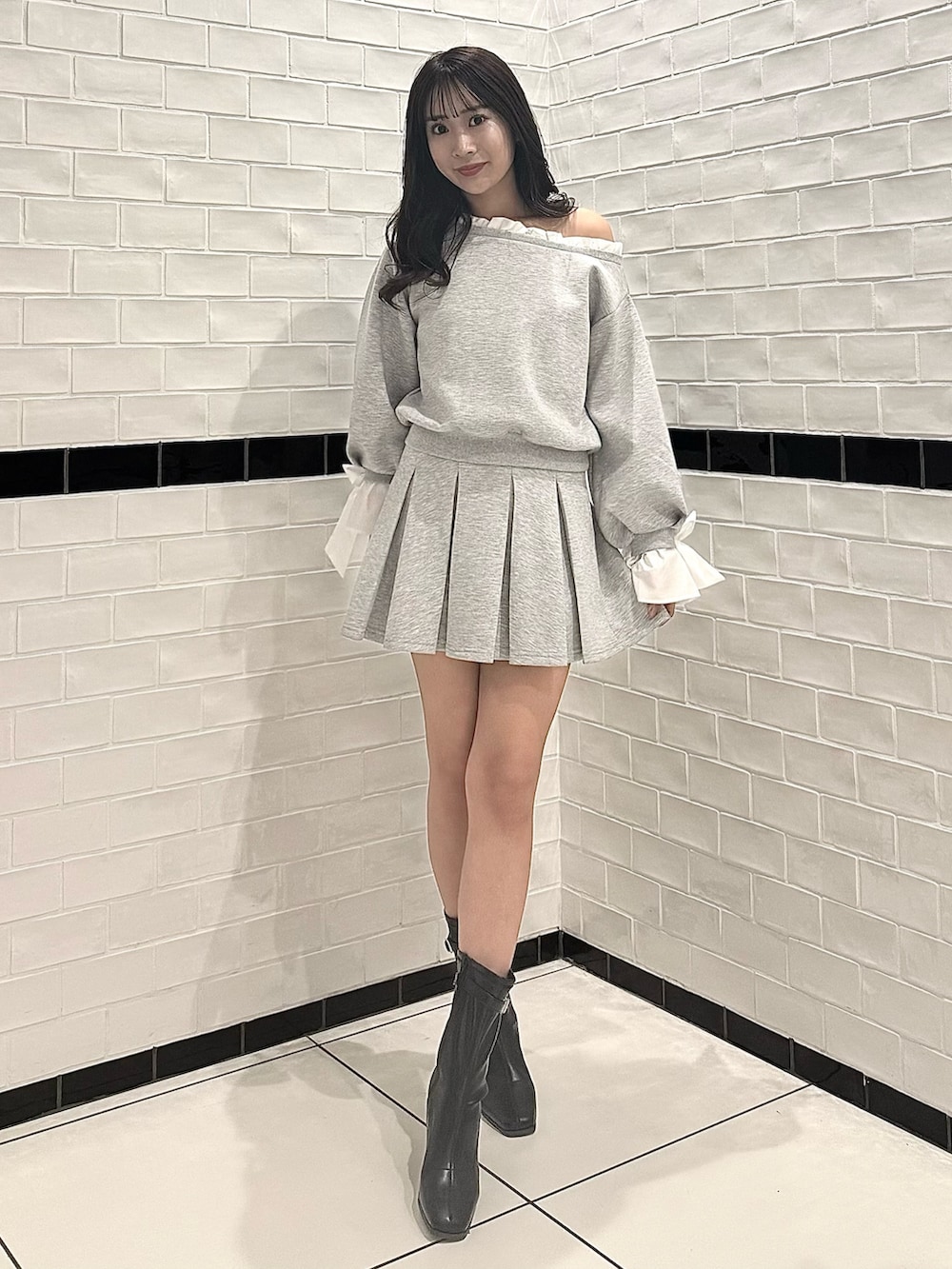 グレー系のTシャツ/カットソー、グレー系のスカート、ブラック系のブーツを着用したレディースの春コーディネートの2枚目の写真