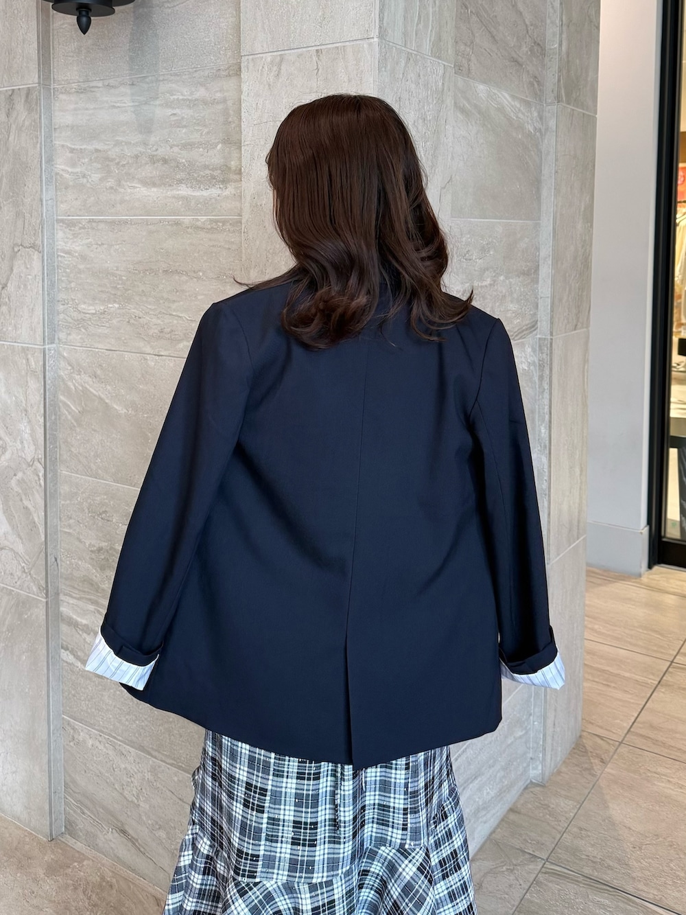 ブルー系のテーラードジャケット、ブラック系のワンピース、ブラック系のパンプスを着用したレディースの春コーディネートの6枚目の写真