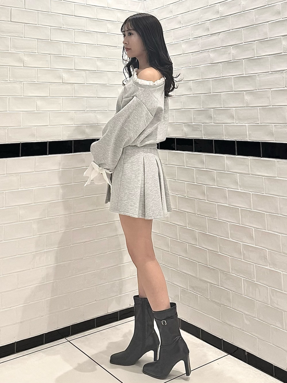 グレー系のTシャツ/カットソー、グレー系のスカート、ブラック系のブーツを着用したレディースの春コーディネートの5枚目の写真