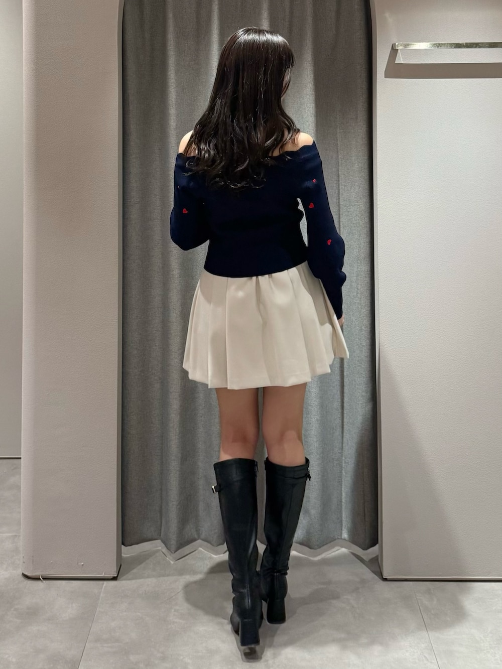 ブルー系のニット/セーター、ホワイト系のスカート、ブラック系のブーツを着用したレディースの冬コーディネートの5枚目の写真