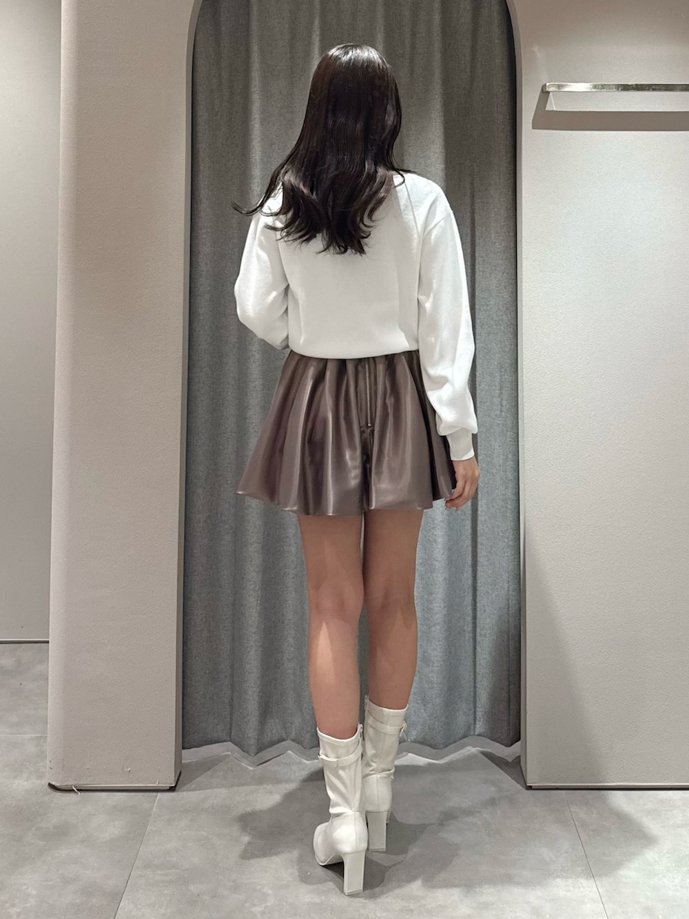 ホワイト系のカーディガン/ボレロ、ブラウン系のスカート、ホワイト系のブーツを着用したレディースの春コーディネートの5枚目の写真