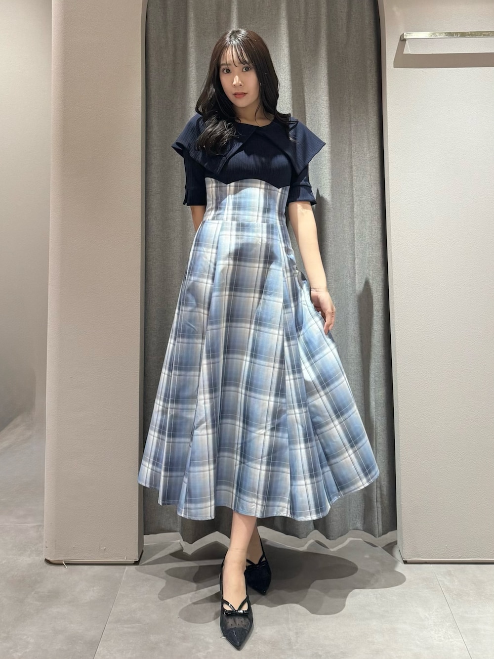 ブルー系のワンピース、ブラック系のパンプスを着用したレディースの春コーディネートの2枚目の写真