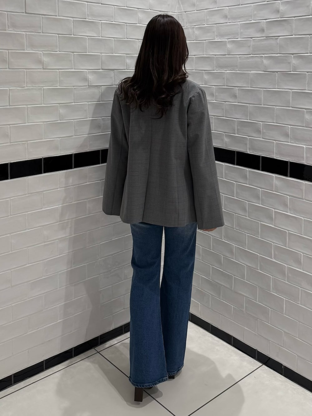 グレー系のテーラードジャケット、ブルー系のデニムパンツ、ブラウン系のブーツを着用したレディースの冬コーディネートの5枚目の写真