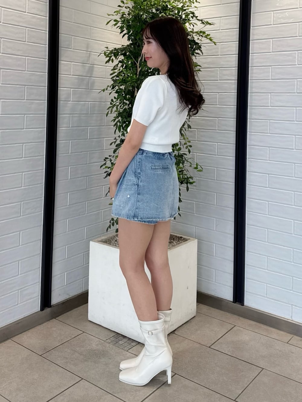 ホワイト系のニット/セーター、ブルー系のデニムパンツ、ホワイト系のブーツを着用したレディースの春コーディネートの4枚目の写真