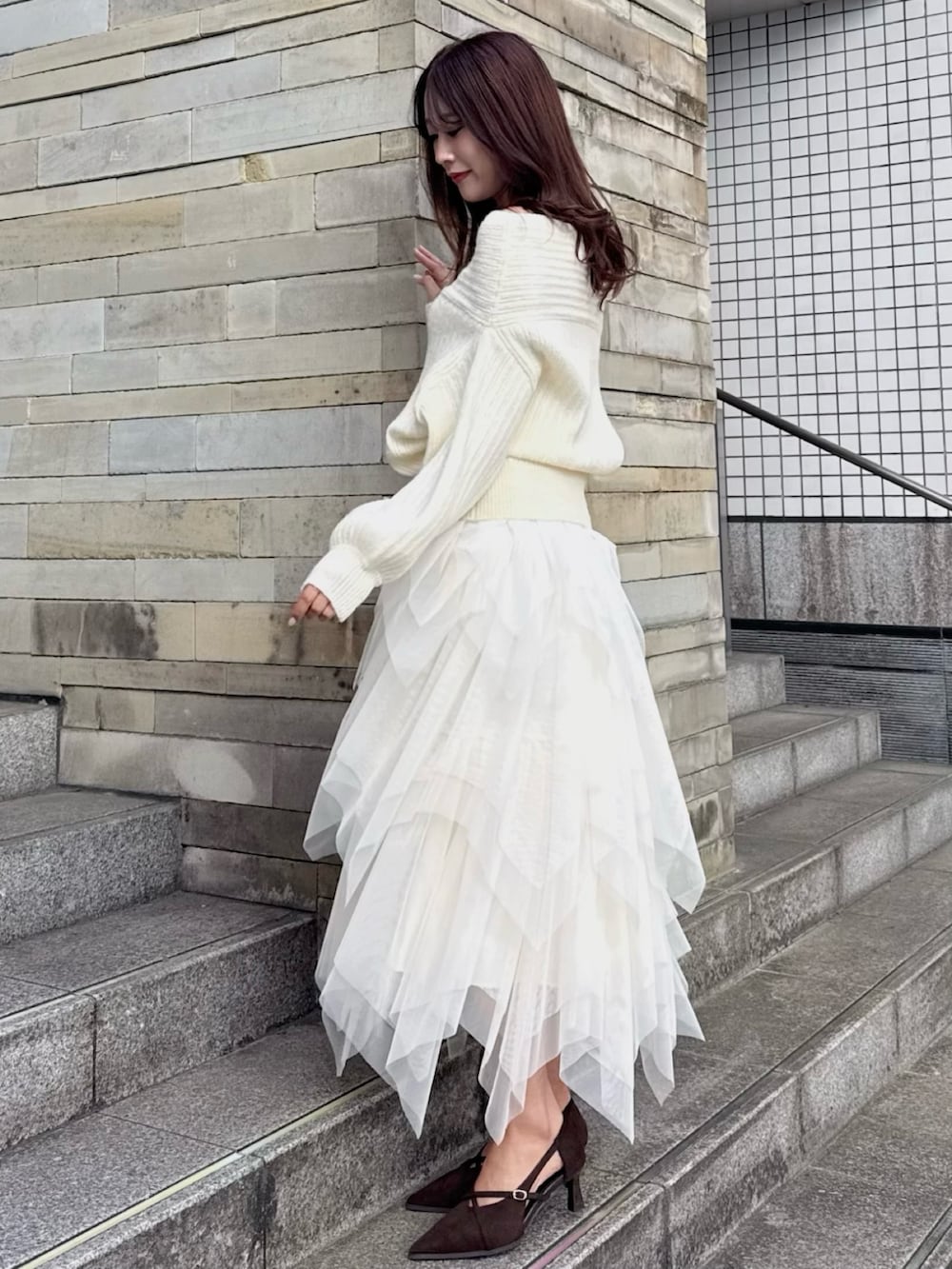 ブラウン系のパンプス、ホワイト系のニット/セーター、ホワイト系のスカートを着用したレディースの冬コーディネートの2枚目の写真
