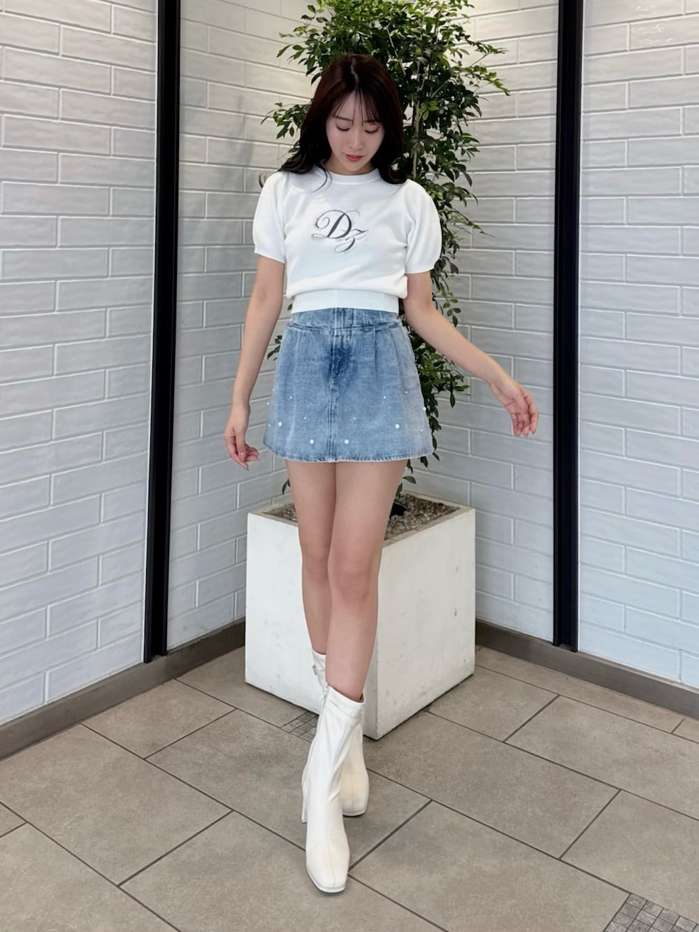 ホワイト系のニット/セーター、ブルー系のデニムパンツ、ホワイト系のブーツを着用したレディースの春コーディネートの2枚目の写真