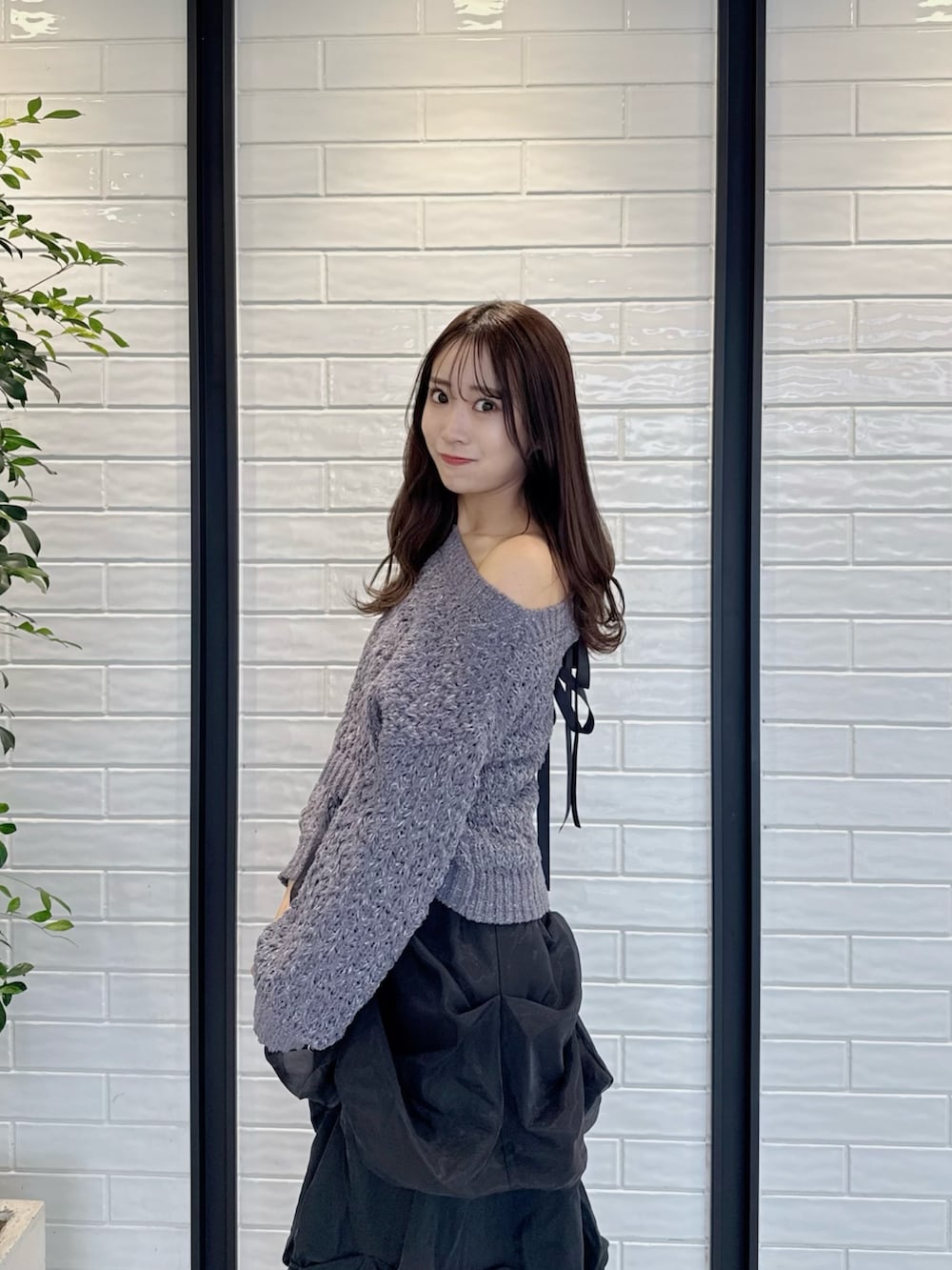 グレー系のニット/セーター、ブラック系のスカート、ブラック系のブーツを着用したレディースの冬コーディネートの6枚目の写真