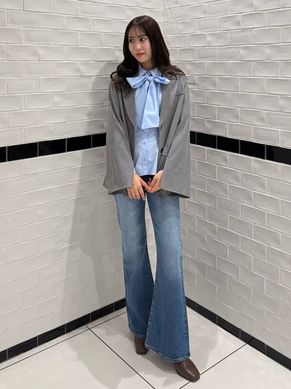 グレー系のテーラードジャケット、ブルー系のデニムパンツ、ブラウン系のブーツを着用したレディースの冬コーディネートの2枚目の写真