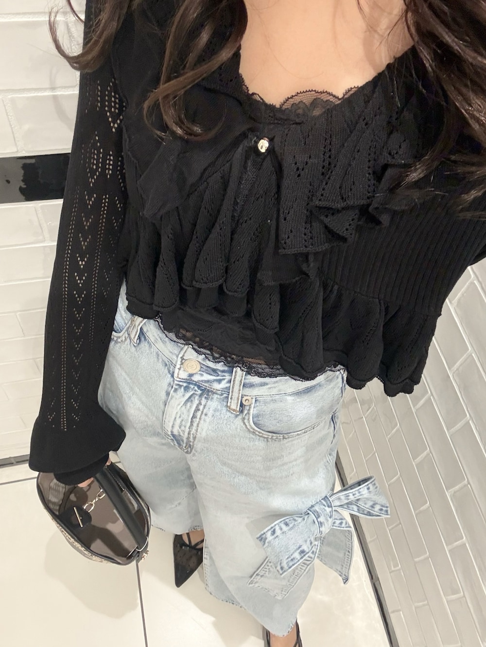 ブラック系のカーディガン/ボレロ、ブラック系のキャミソール、ブルー系のデニムパンツを着用したレディースの春コーディネートの6枚目の写真