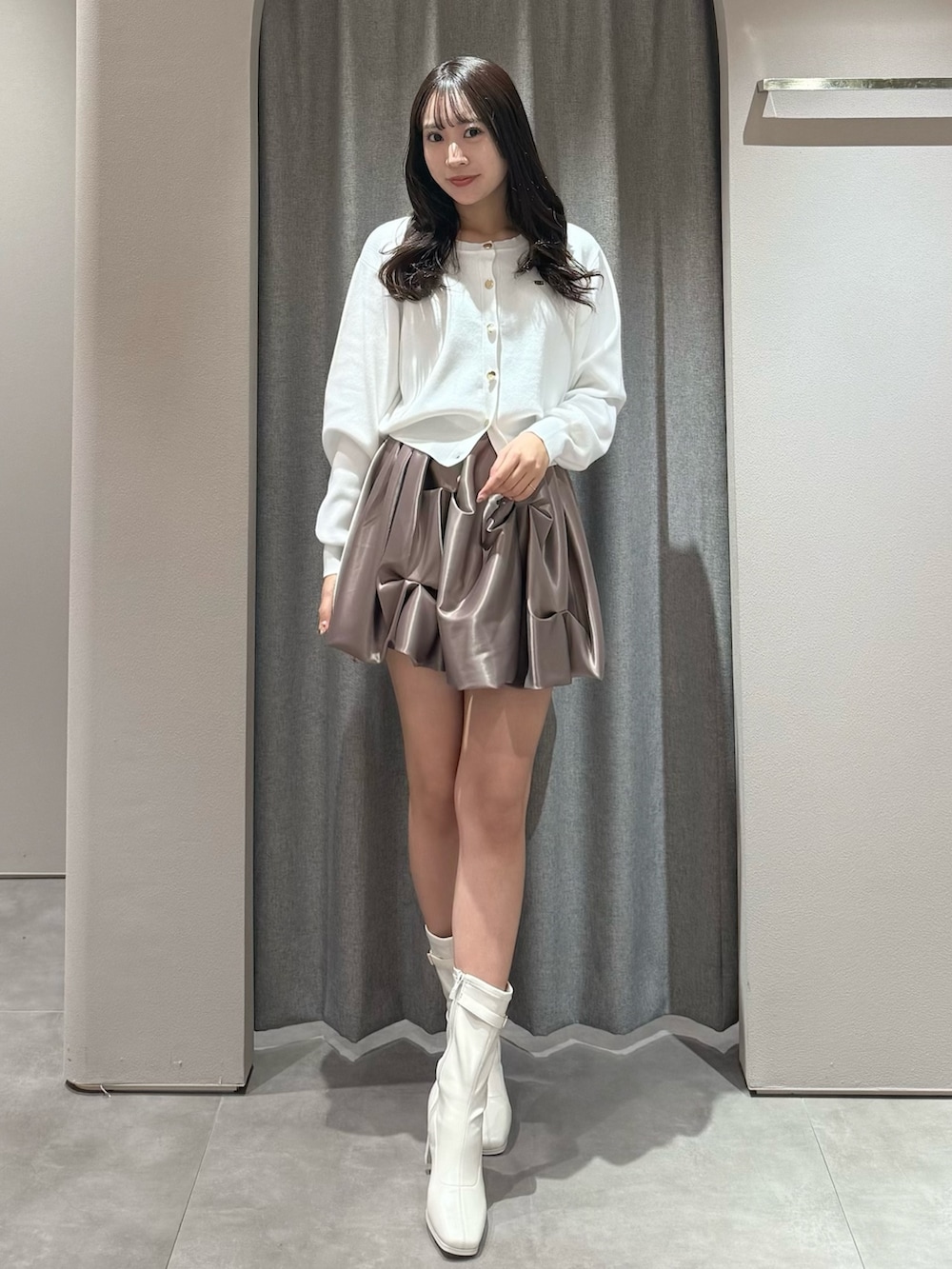 ホワイト系のカーディガン/ボレロ、ブラウン系のスカート、ホワイト系のブーツを着用したレディースの春コーディネートの2枚目の写真
