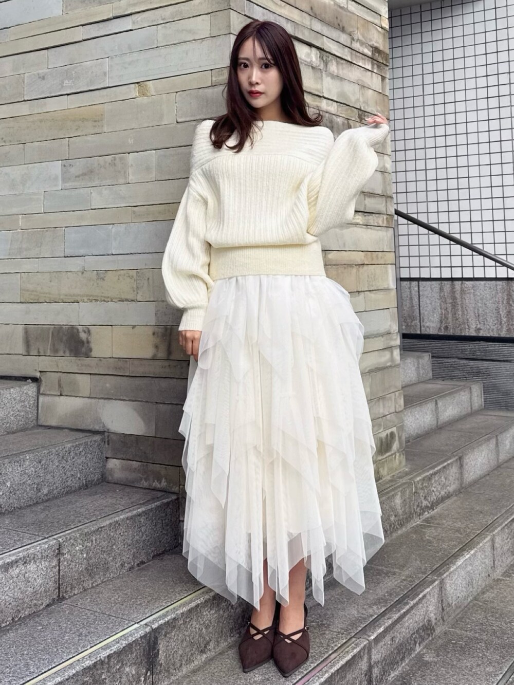ブラウン系のパンプス、ホワイト系のニット/セーター、ホワイト系のスカートを着用したレディースの冬コーディネートの3枚目の写真