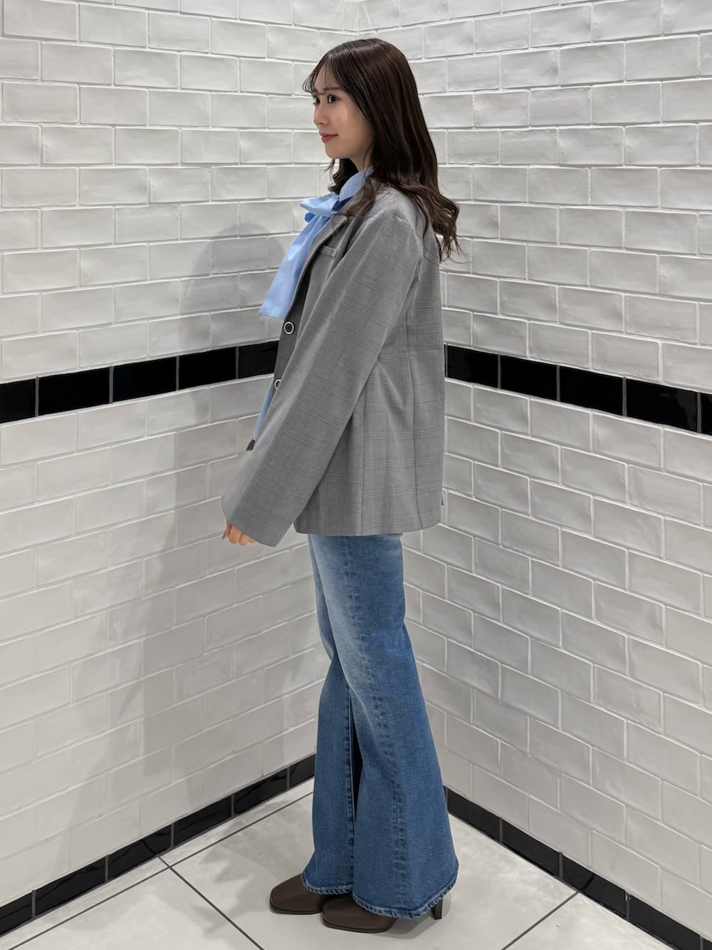 グレー系のテーラードジャケット、ブルー系のデニムパンツ、ブラウン系のブーツを着用したレディースの冬コーディネートの4枚目の写真