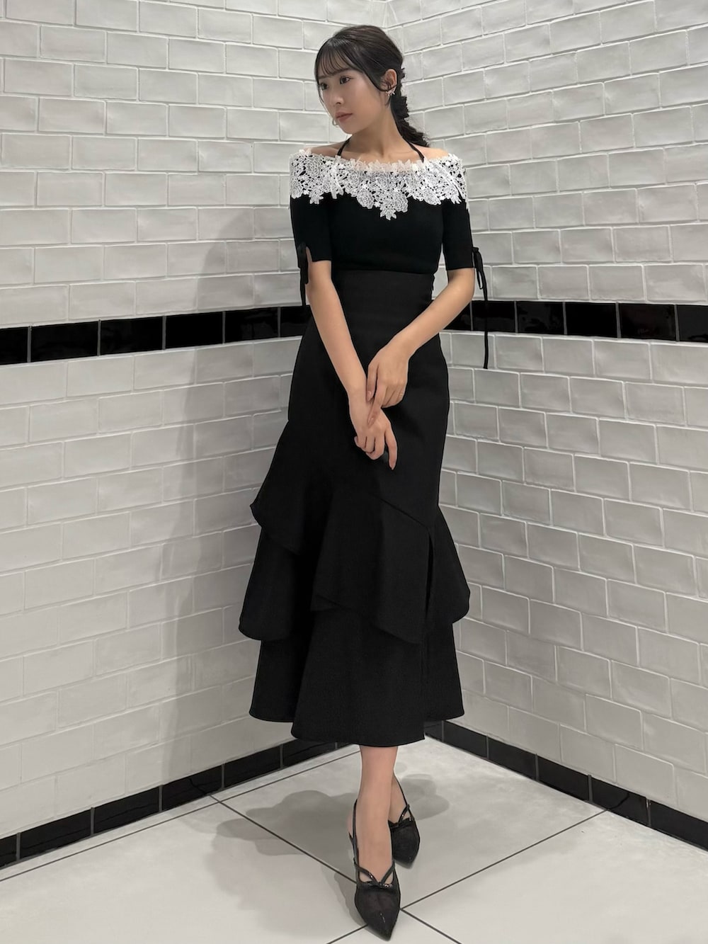 ブラック系のニット/セーター、ブラック系のスカート、ブラック系のパンプスを着用したレディースの春コーディネートの2枚目の写真