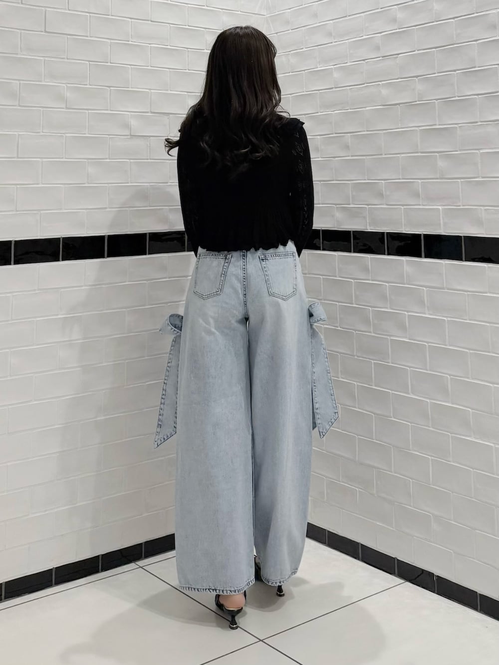 ブラック系のカーディガン/ボレロ、ブラック系のキャミソール、ブルー系のデニムパンツを着用したレディースの春コーディネートの5枚目の写真