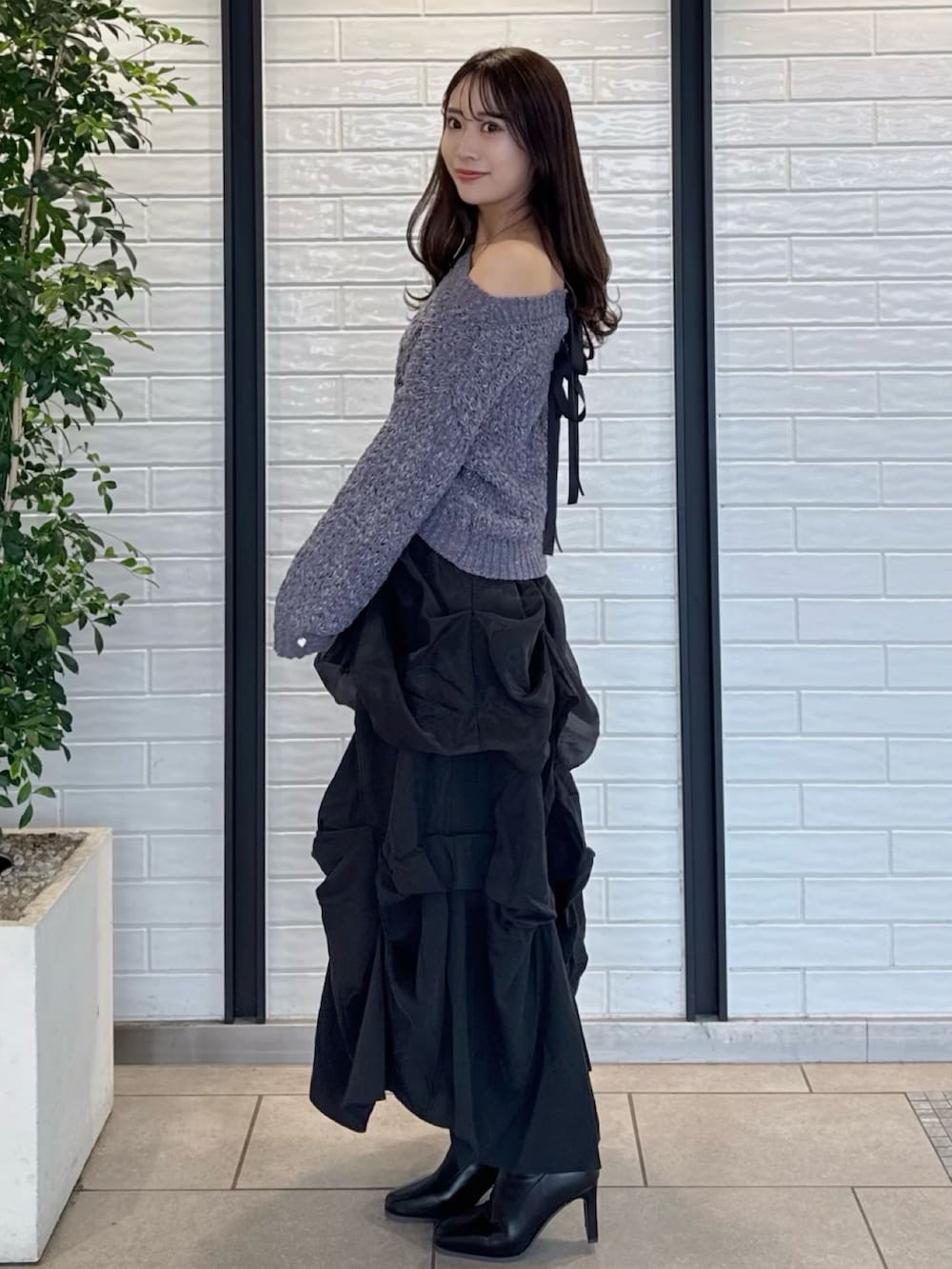 グレー系のニット/セーター、ブラック系のスカート、ブラック系のブーツを着用したレディースの冬コーディネートの3枚目の写真