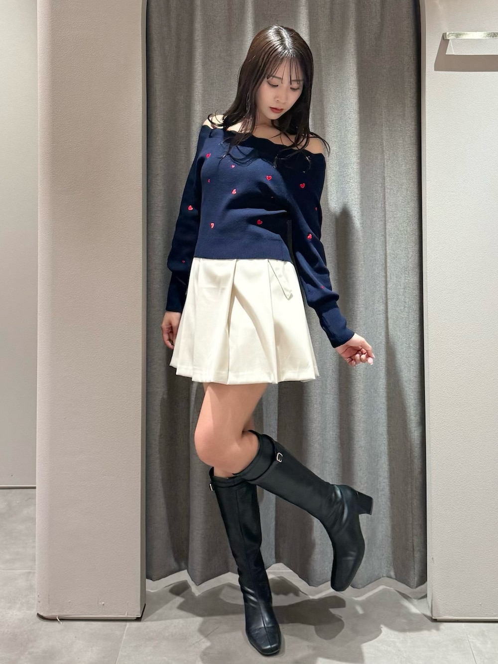 ブルー系のニット/セーター、ホワイト系のスカート、ブラック系のブーツを着用したレディースの冬コーディネートの3枚目の写真