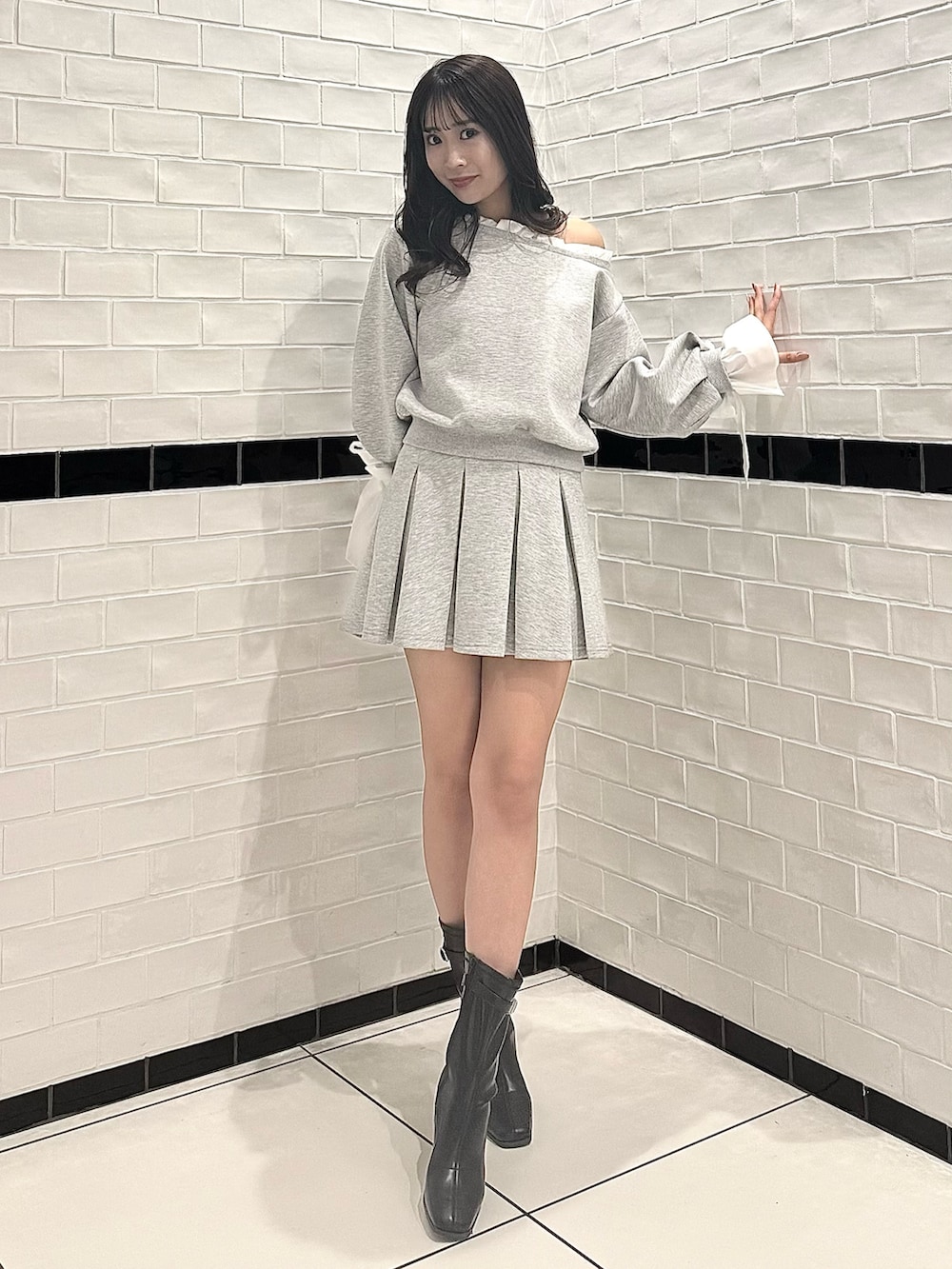 グレー系のTシャツ/カットソー、グレー系のスカート、ブラック系のブーツを着用したレディースの春コーディネートの3枚目の写真