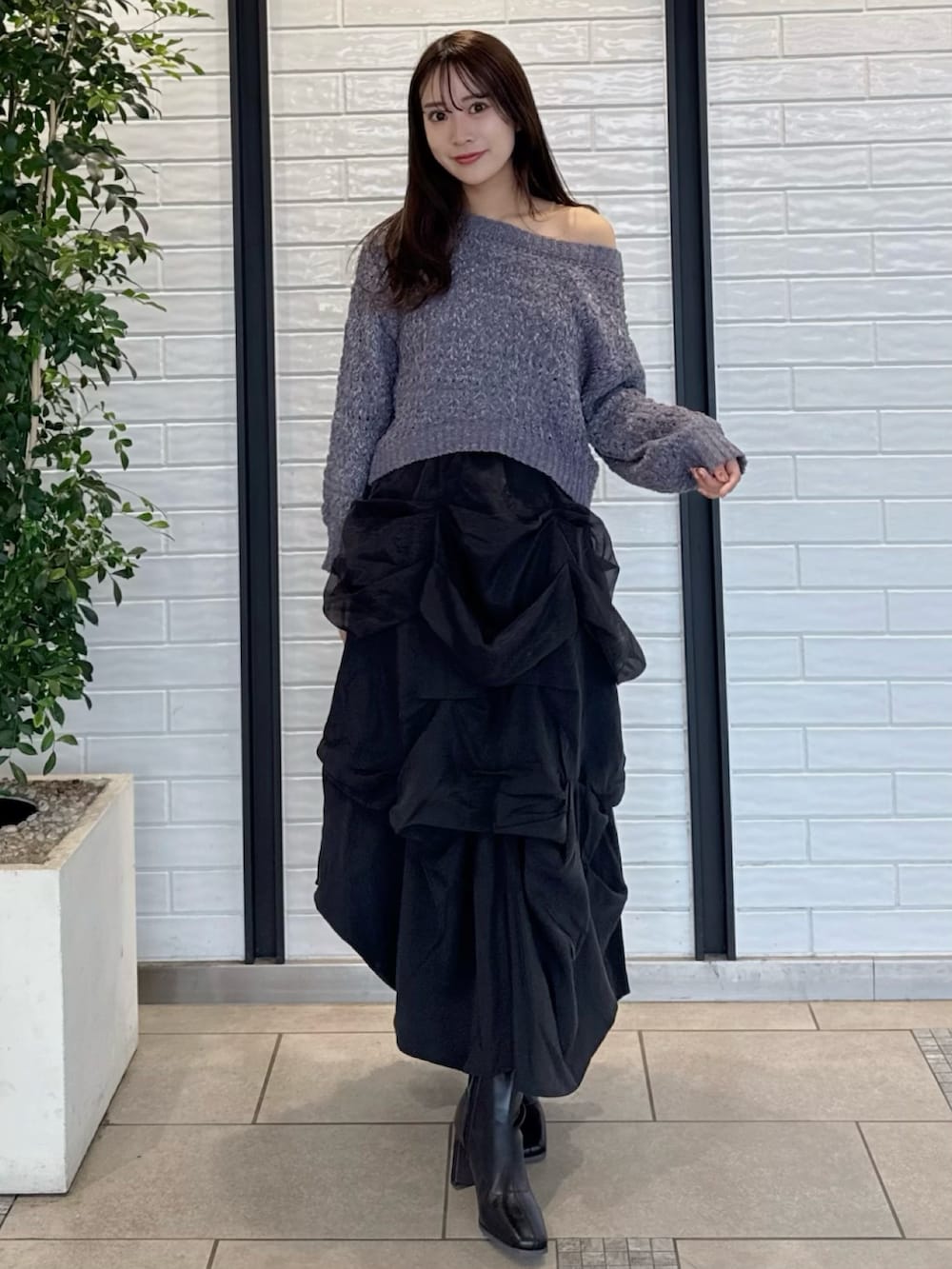 グレー系のニット/セーター、ブラック系のスカート、ブラック系のブーツを着用したレディースの冬コーディネートの2枚目の写真