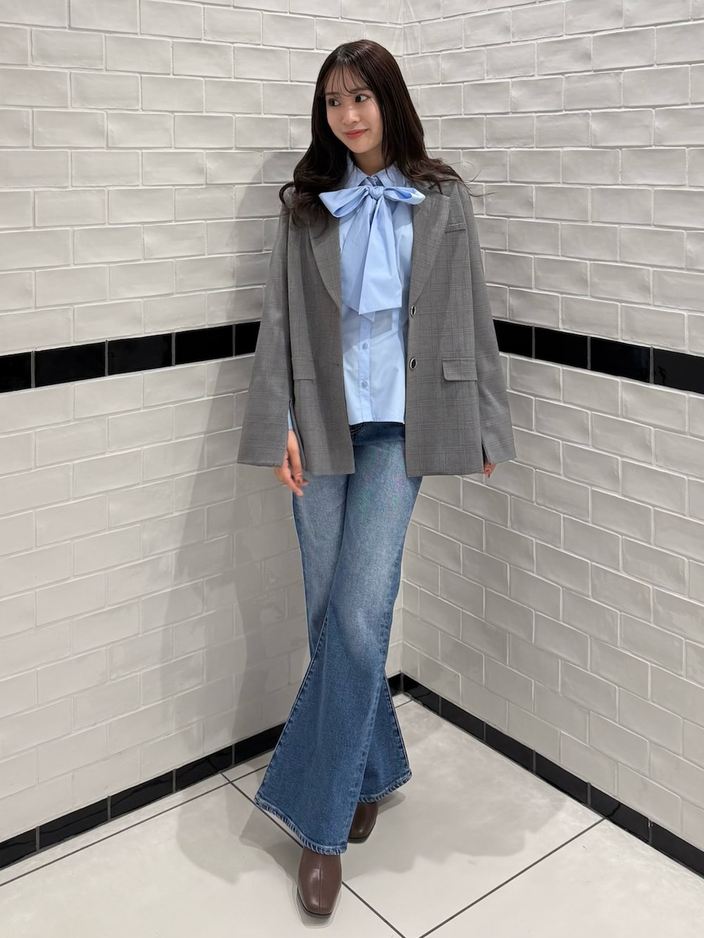 グレー系のテーラードジャケット、ブルー系のデニムパンツ、ブラウン系のブーツを着用したレディースの冬コーディネートの3枚目の写真