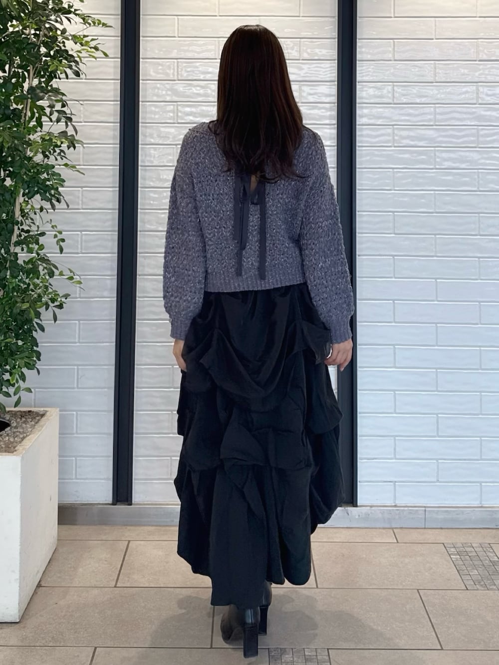 グレー系のニット/セーター、ブラック系のスカート、ブラック系のブーツを着用したレディースの冬コーディネートの4枚目の写真