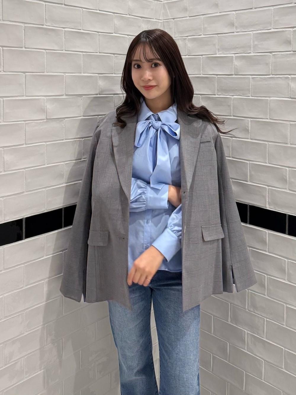 グレー系のテーラードジャケット、ブルー系のデニムパンツ、ブラウン系のブーツを着用したレディースの冬コーディネートの7枚目の写真