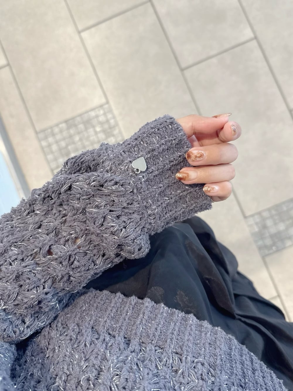 グレー系のニット/セーター、ブラック系のスカート、ブラック系のブーツを着用したレディースの冬コーディネートの7枚目の写真