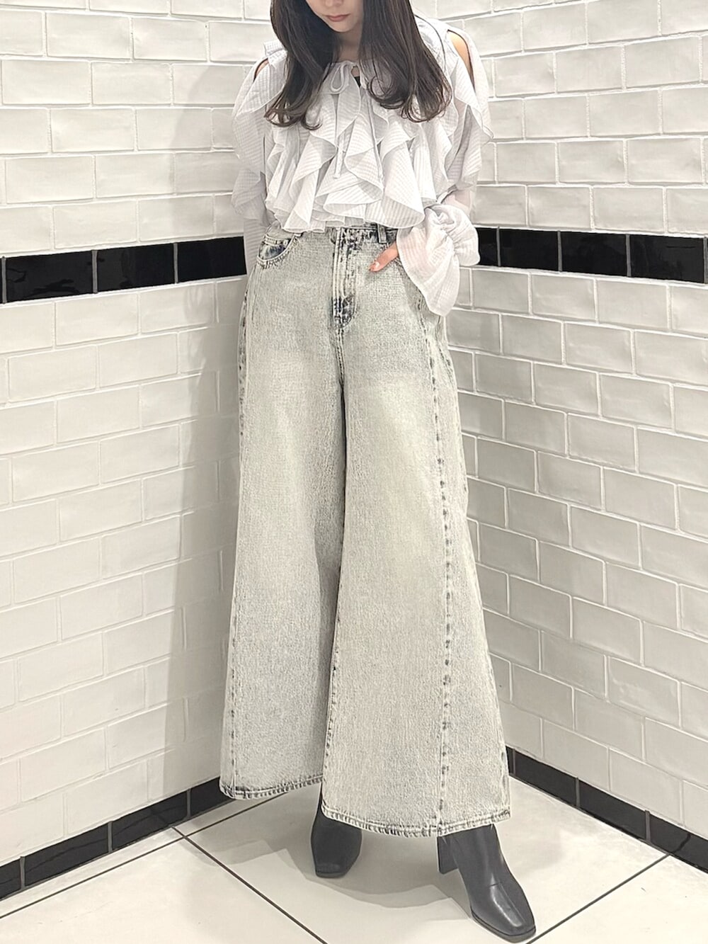 ブラック系のブーツ、グレー系のシャツ/ブラウス、ブルー系のデニムパンツを着用したレディースの春コーディネートの2枚目の写真