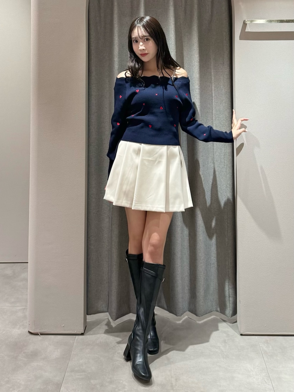 ブルー系のニット/セーター、ホワイト系のスカート、ブラック系のブーツを着用したレディースの冬コーディネートの2枚目の写真