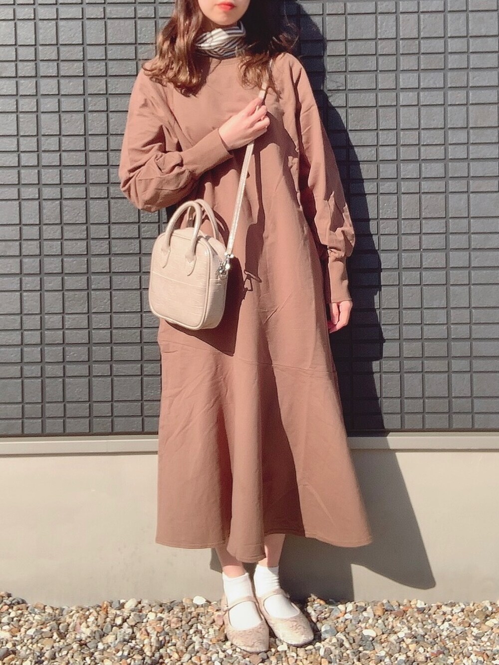 ブラウン系のワンピース、ベージュ系のショルダーバッグ、ホワイト系のその他シューズを着用したレディースの冬コーディネートの2枚目の写真