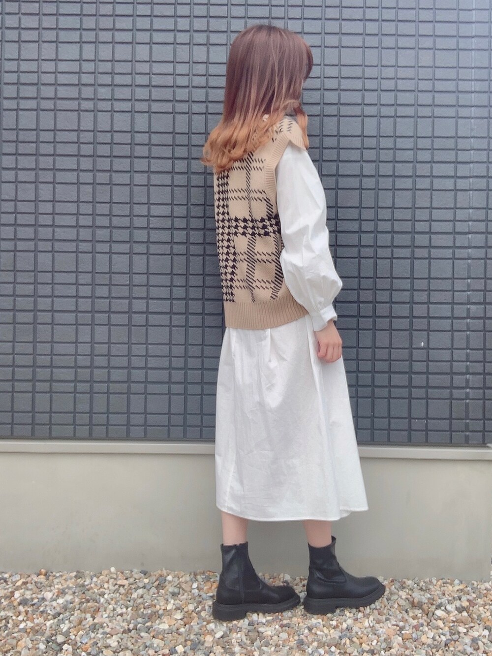 ホワイト系のシャツワンピース、ベージュ系のベスト、ブラック系のブーツを着用したレディースの秋コーディネートの2枚目の写真