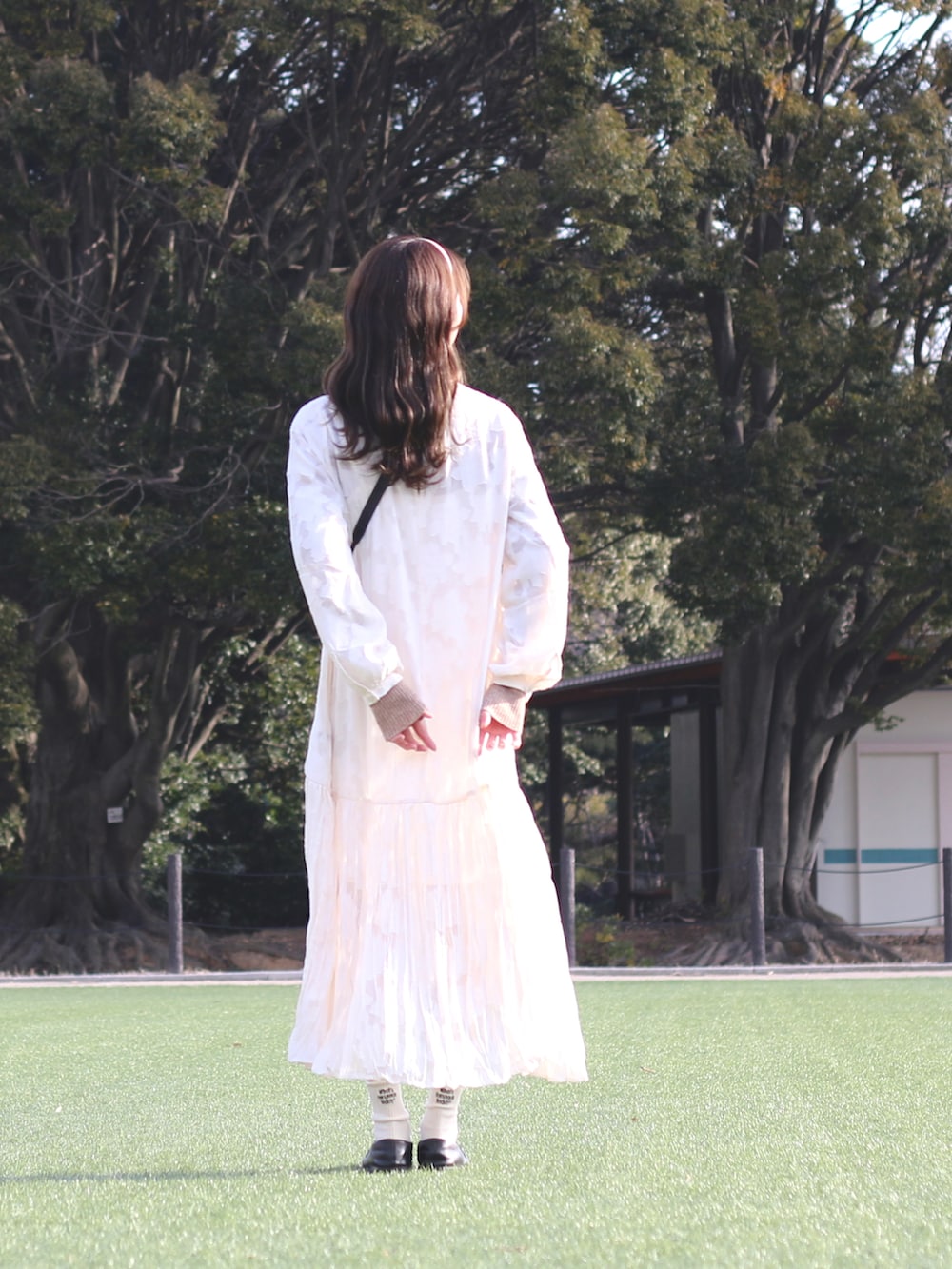 ホワイト系のワンピース、ベージュ系のニット/セーターを着用したレディースの春コーディネートの2枚目の写真