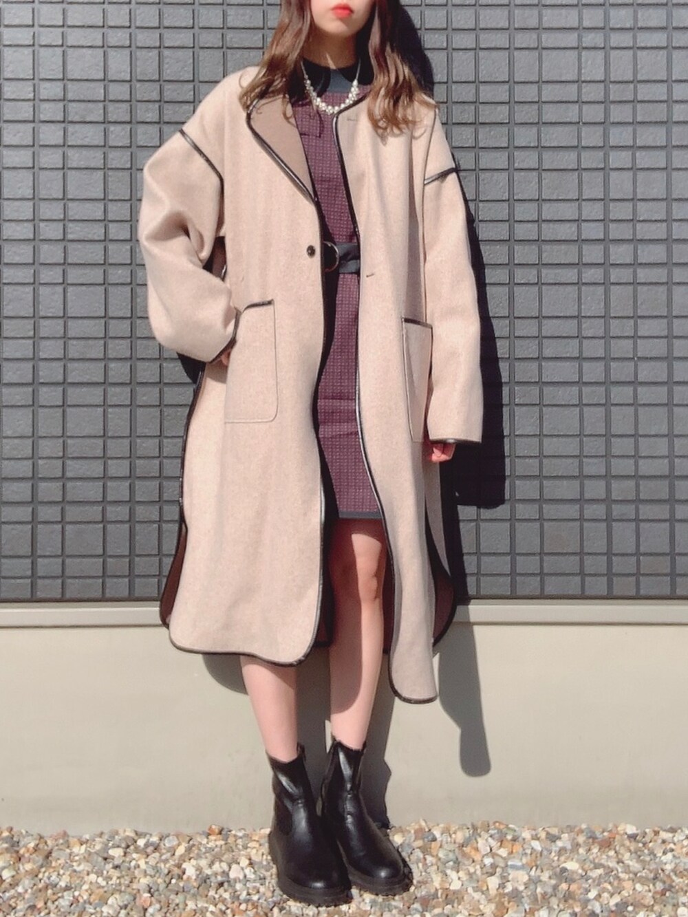 グリーン系のワンピース、ベージュ系のノーカラーコート、ブラック系のブーツを着用したレディースの秋コーディネートの2枚目の写真