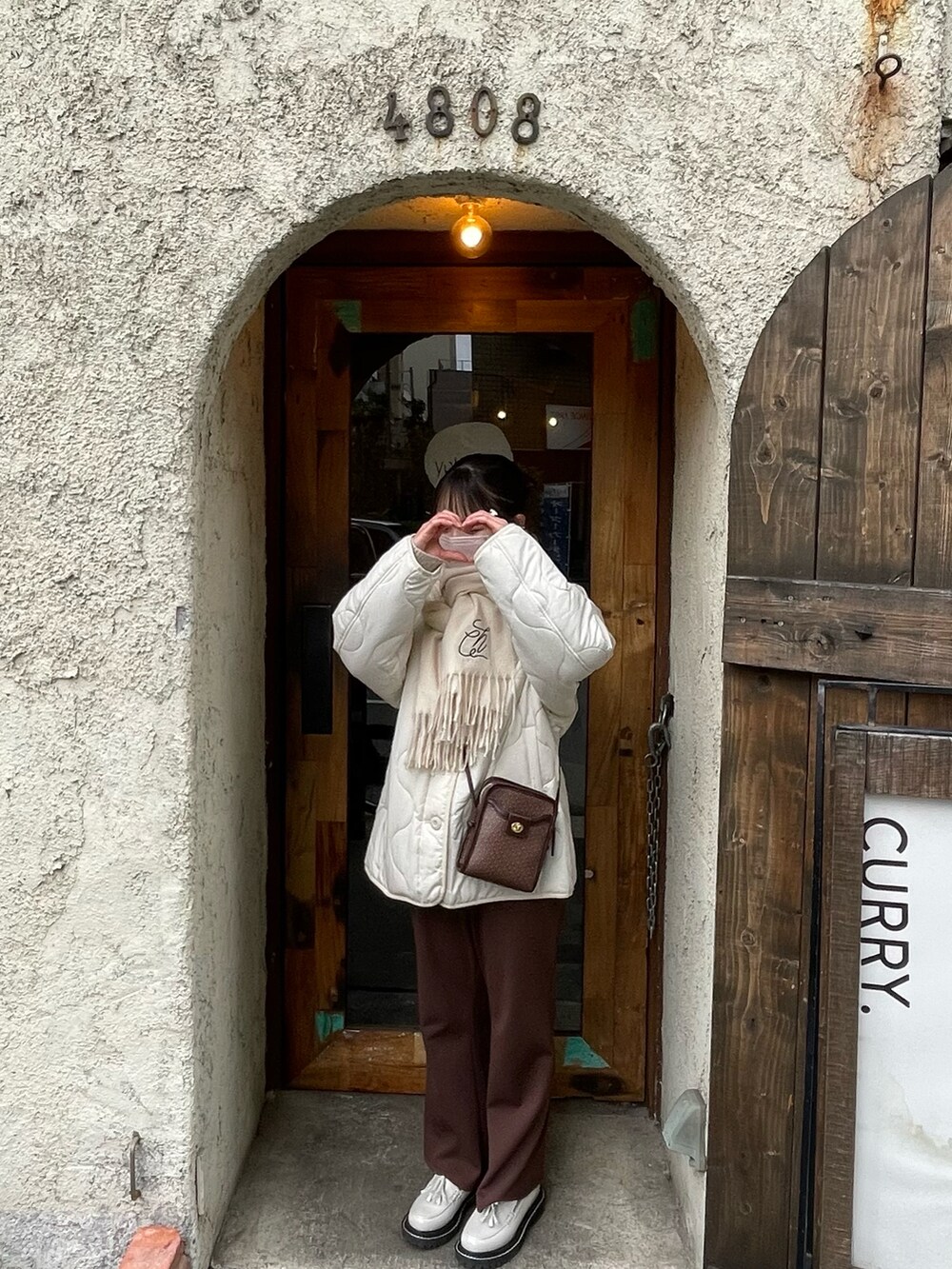 ホワイト系のノーカラージャケット、ブラウン系のショルダーバッグ、ホワイト系のローファーを着用したレディースの冬コーディネートの2枚目の写真