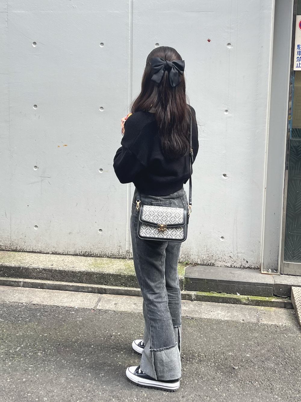 ブラック系のデニムパンツ、ブラック系のスニーカー、ブラック系のカーディガン/ボレロを着用したレディースの秋コーディネートの2枚目の写真