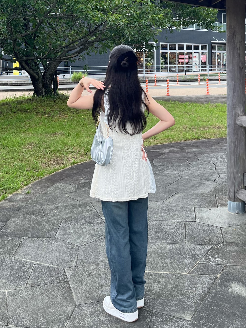 ホワイト系のキャミソール、シルバー系のハンドバッグ、ブルー系のデニムパンツを着用したレディースの夏コーディネートの2枚目の写真