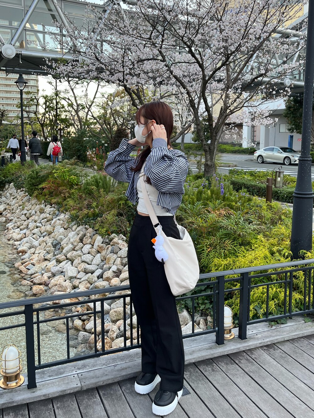 ブラック系のシャツ/ブラウス、ホワイト系のショルダーバッグ、ブラック系のスラックスを着用したレディースの春コーディネートの2枚目の写真